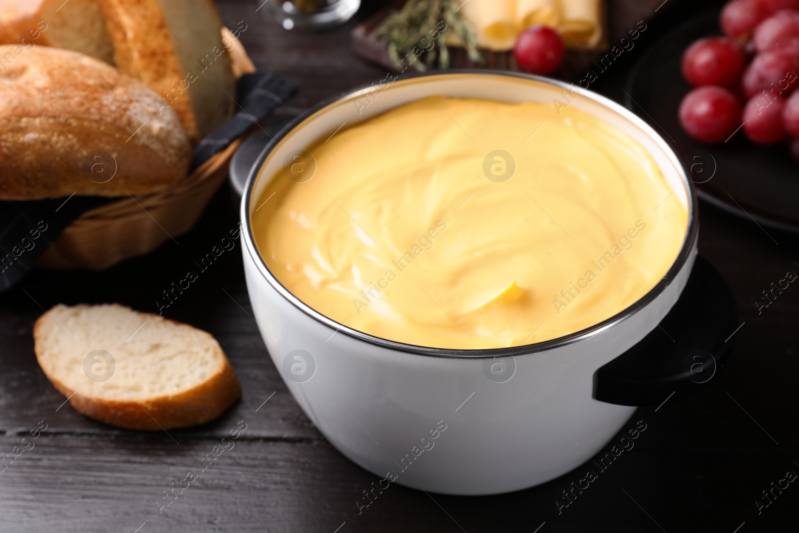 Photo of Pot with delicious cheese fondue on wooden table