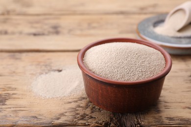 Photo of Bowl of active dry yeast on wooden table, closeup. Space for text