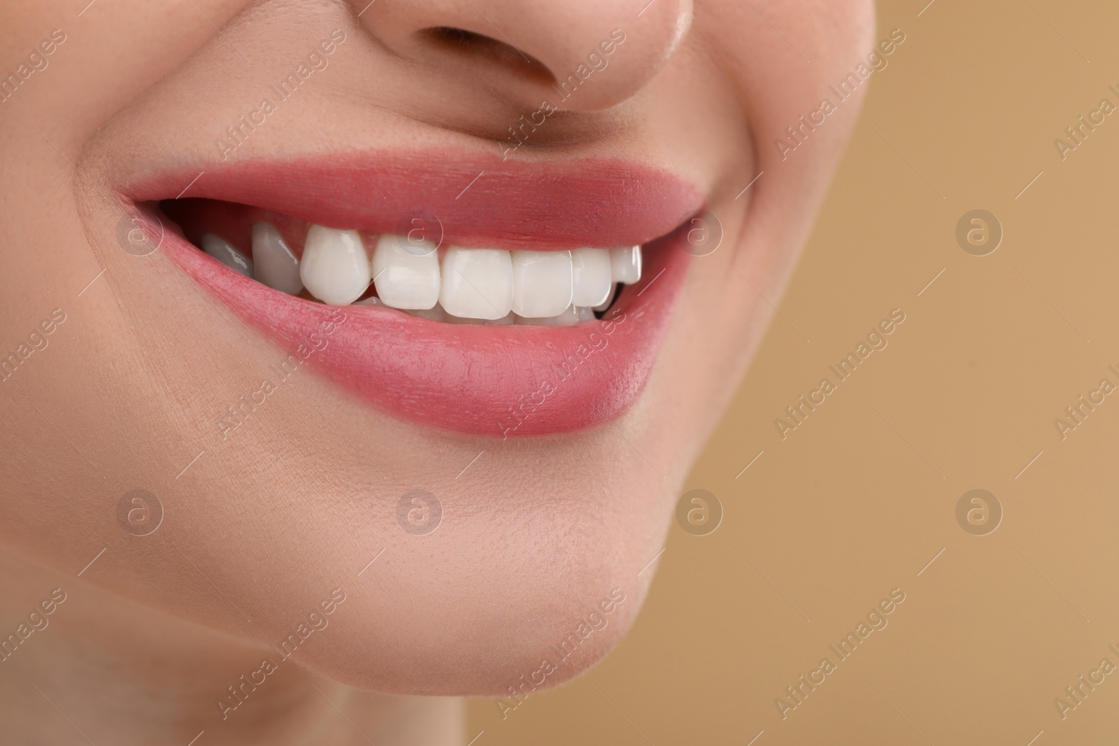Photo of Young woman with beautiful smile on beige background, closeup