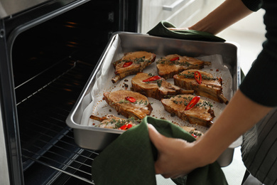 Woman taking delicious ribs out of oven, closeup