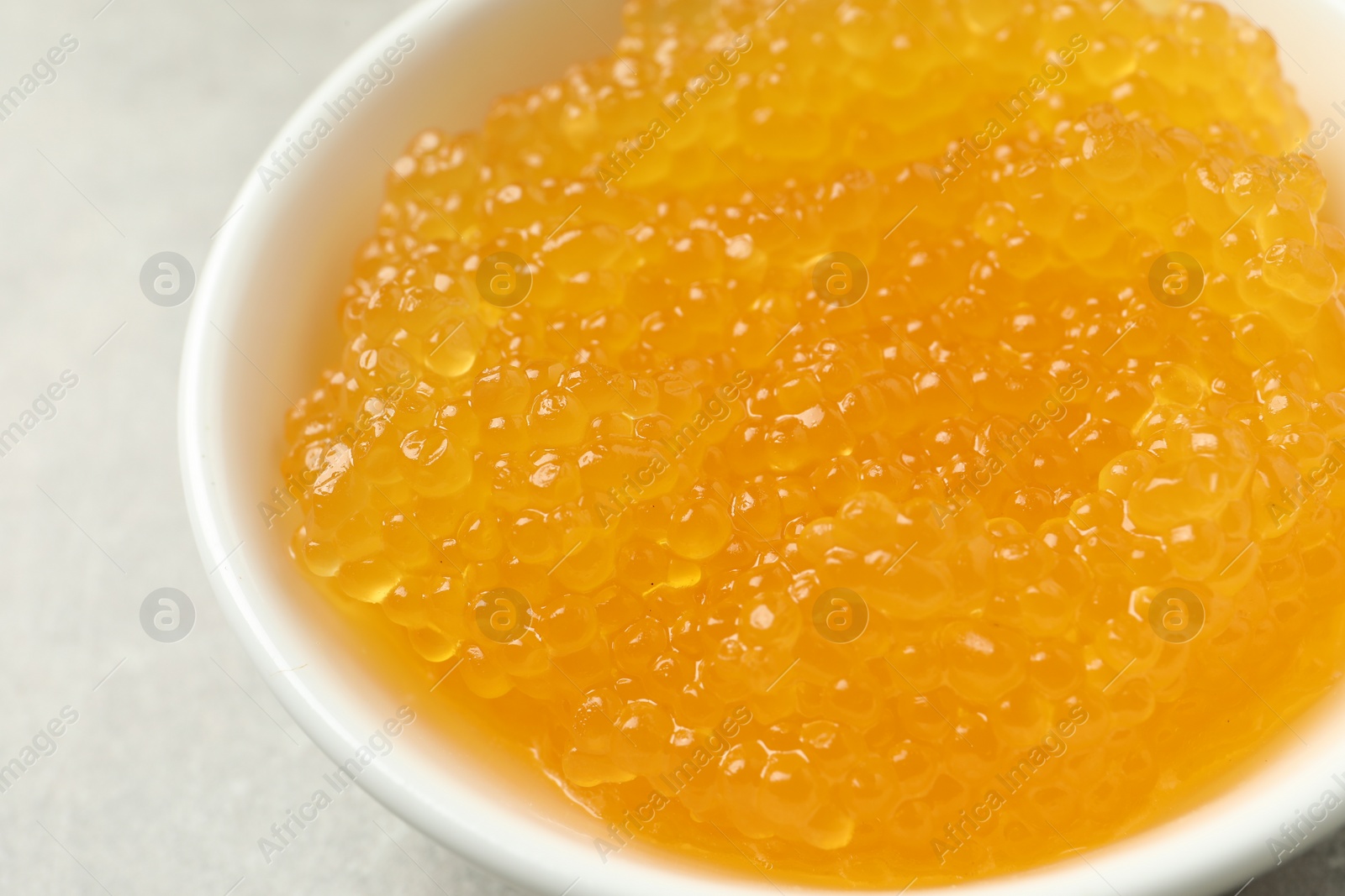 Photo of Fresh pike caviar in bowl on light grey table, closeup