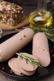 Photo of Delicious liver sausages with rosemary on brown textured table