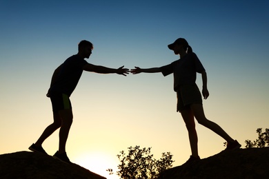 Photo of Hiker helping friend outdoors at sunset. Help and support concept