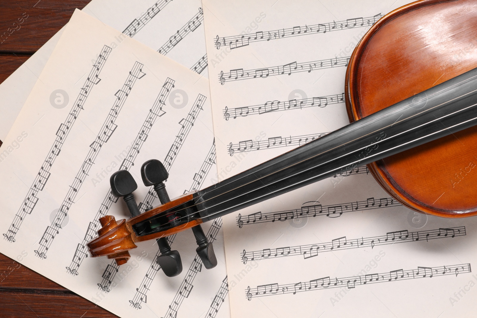 Photo of Violin and music sheets on wooden table, top view