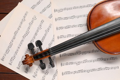 Violin and music sheets on wooden table, top view