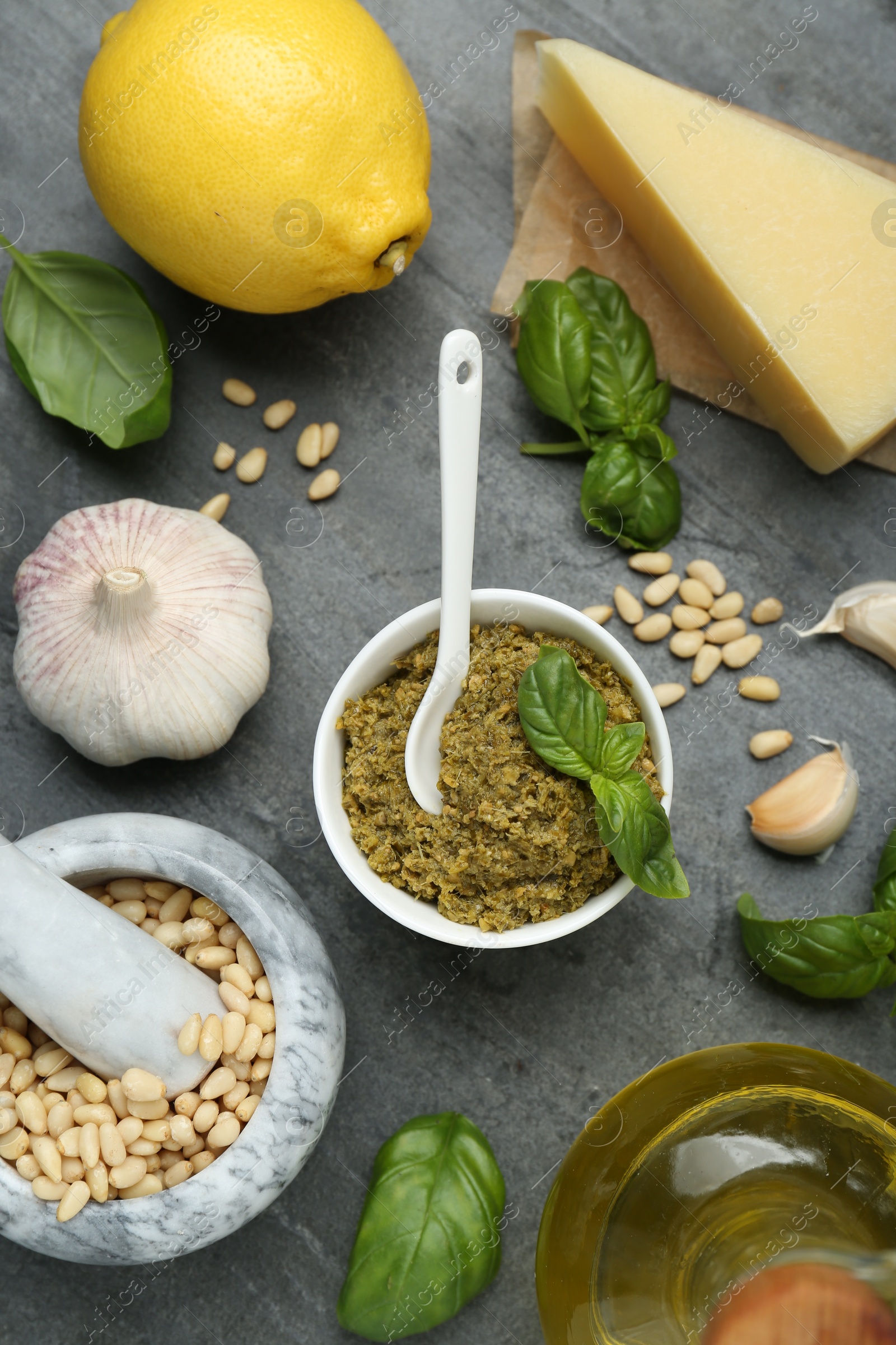 Photo of Delicious pesto sauce and ingredients on grey table, flat lay