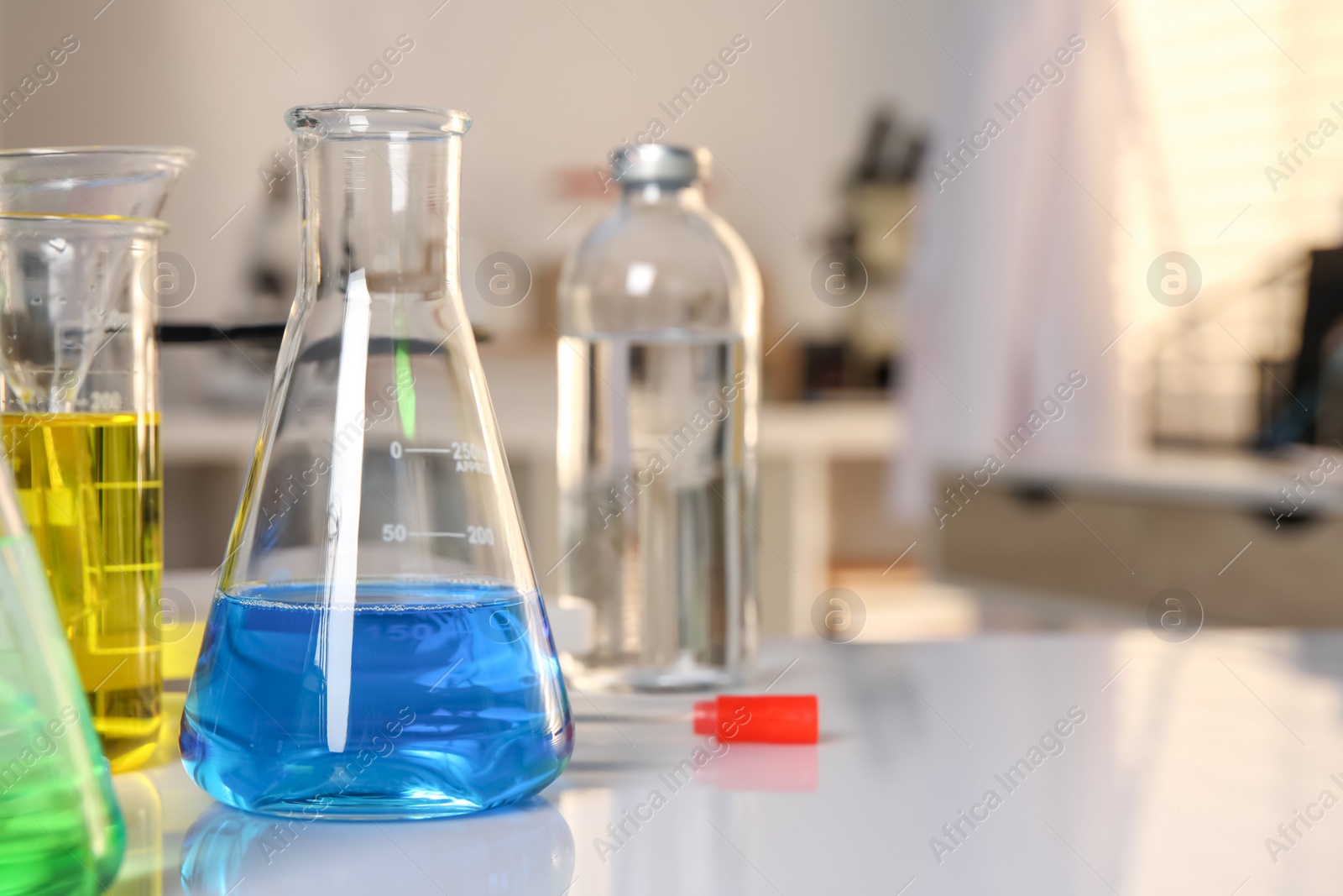 Photo of Laboratory analysis. Glassware with different liquids on white table indoors, closeup. Space for text