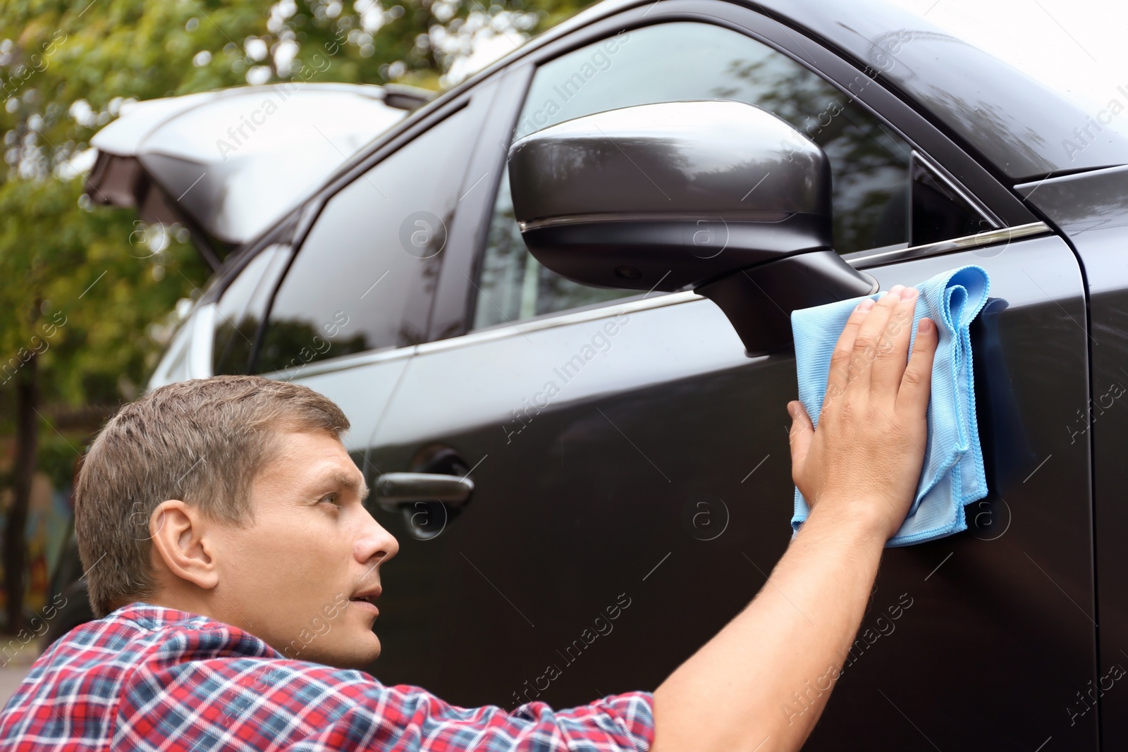 Photo of Man washing car door with rag outdoors