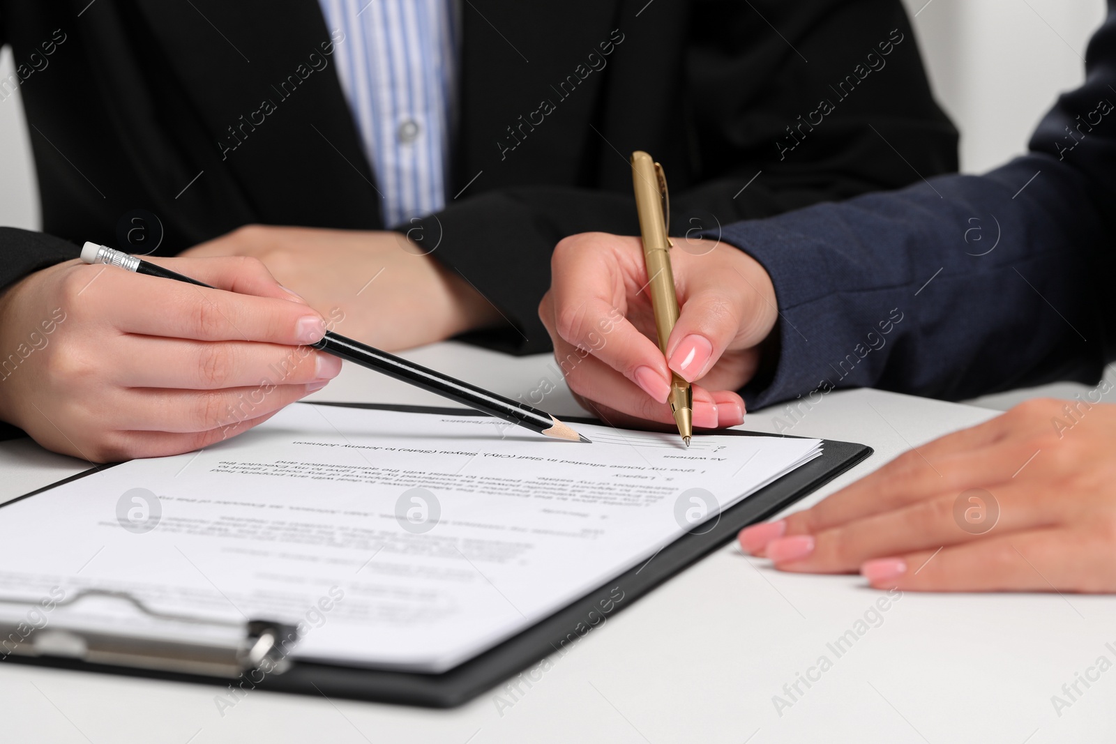 Photo of Businesswoman showing client where to sign document at white table, closeup