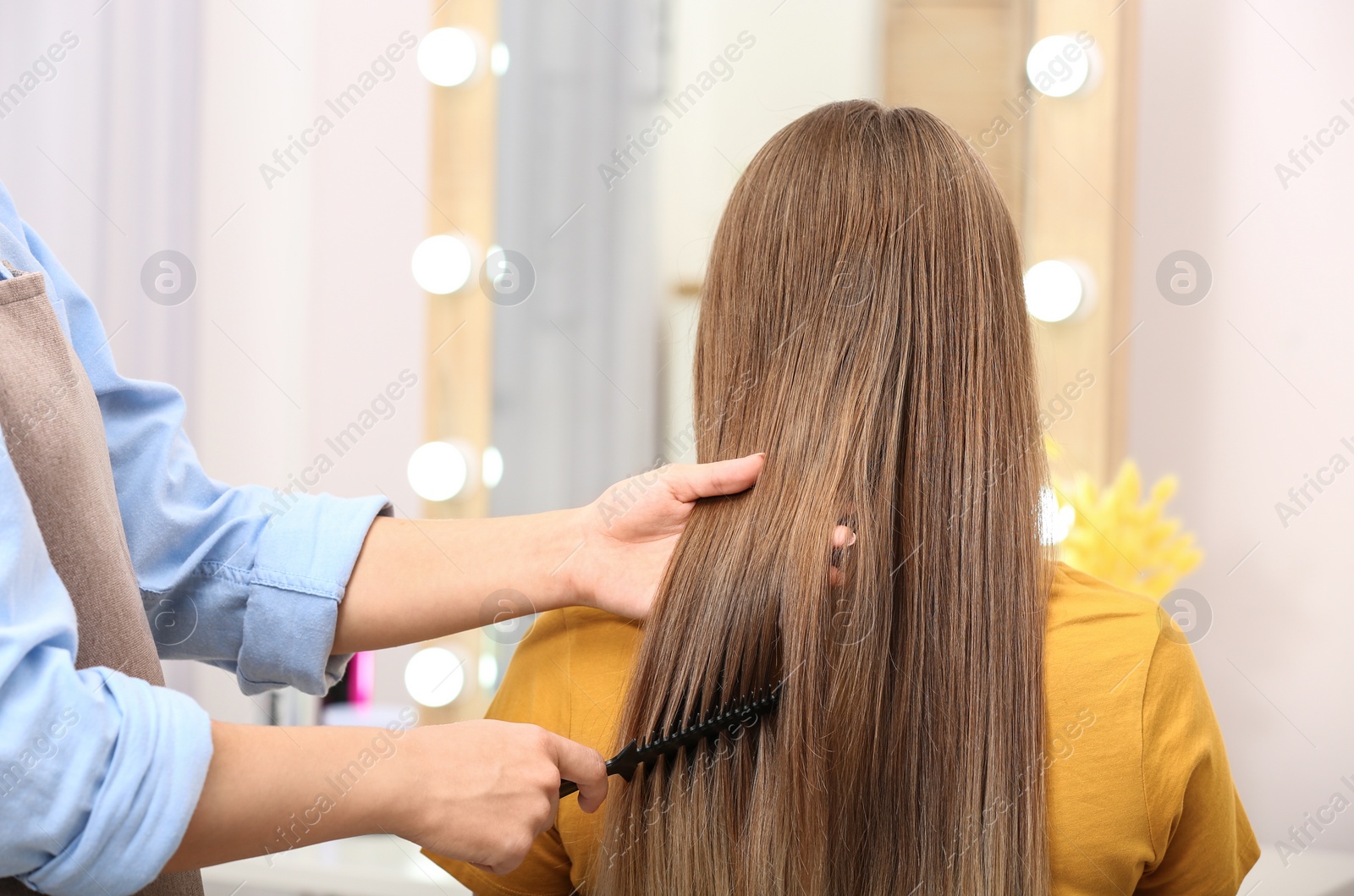 Photo of Professional coiffeuse combing client's hair in salon