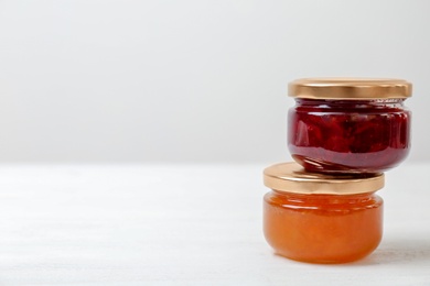 Photo of Two jars with tasty sweet jam on white wooden table