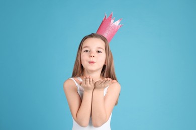Photo of Cute girl in pink crown on light blue background. Little princess