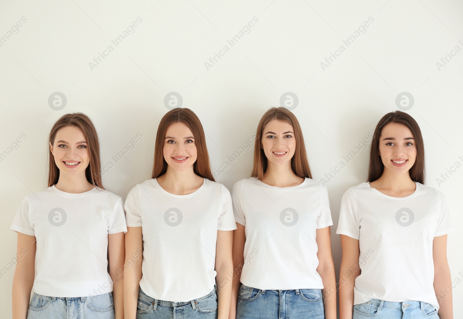 Photo of Beautiful young ladies in jeans and white t-shirts on light background. Woman's Day