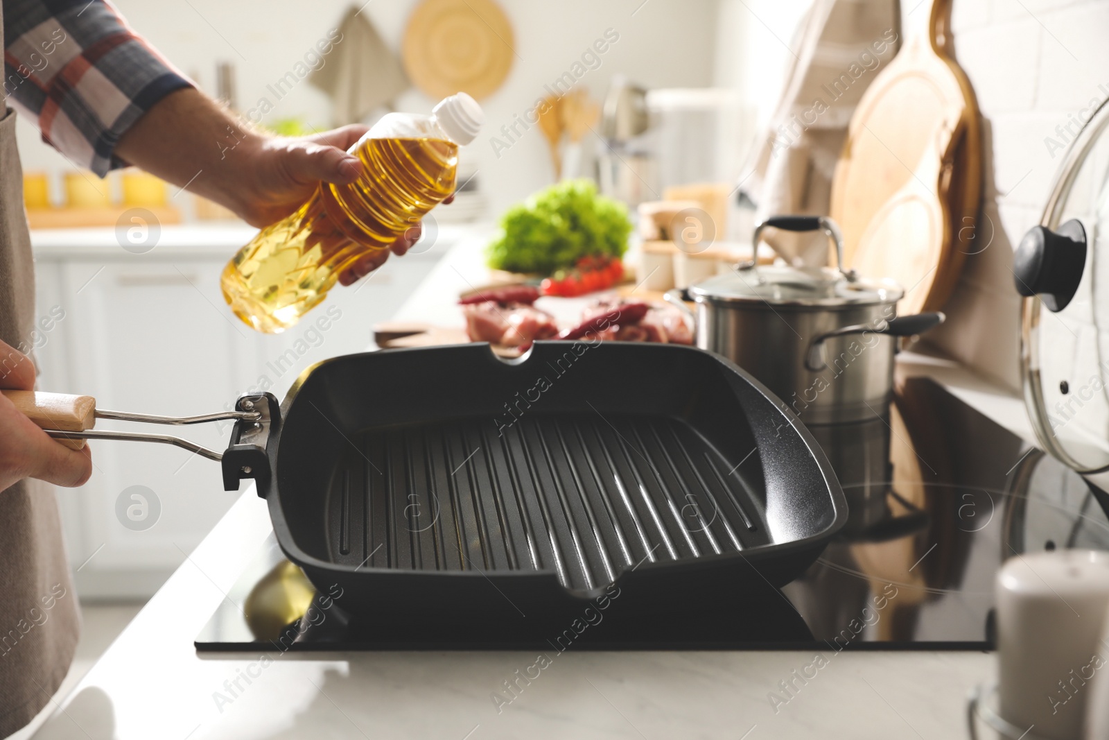 Photo of Man pouring cooking oil into frying pan in kitchen, closeup