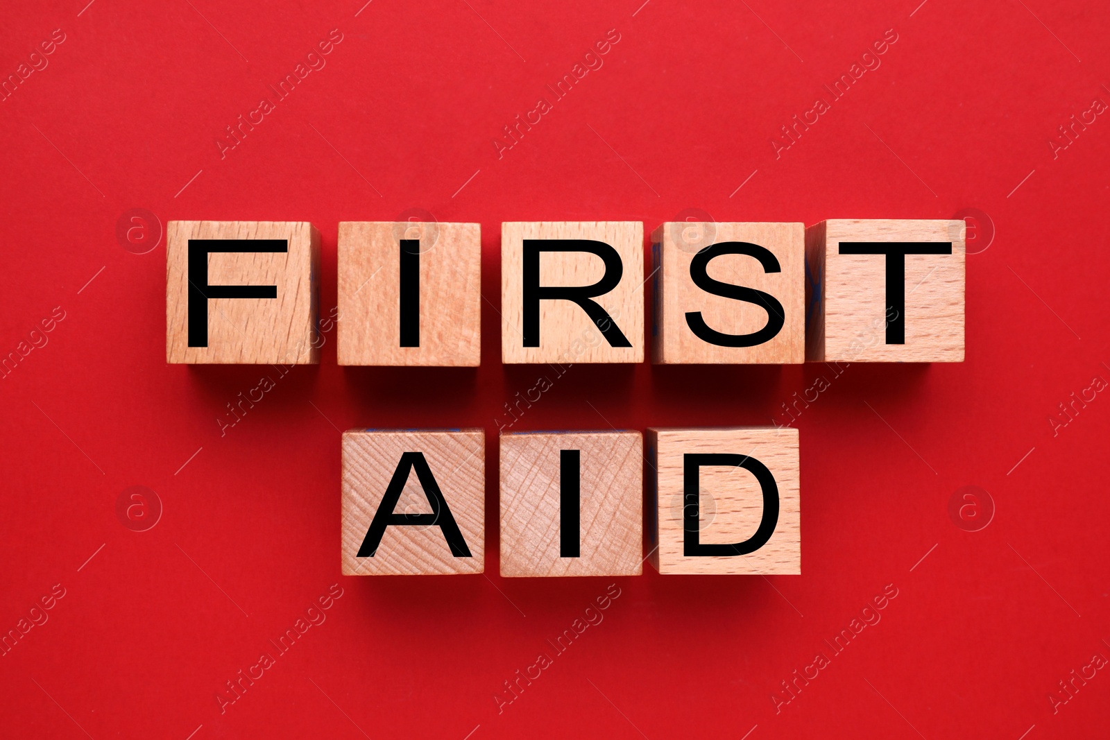 Photo of Words First Aid made of wooden cubes on red background, flat lay