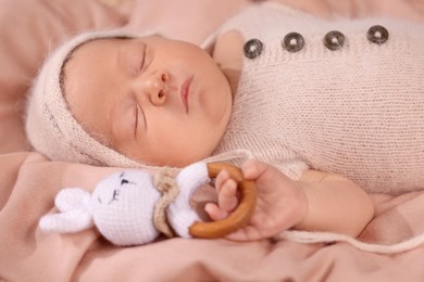 Photo of Cute newborn baby sleeping with rattle on blanket, closeup