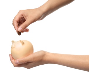 Photo of Young woman putting coin into piggybank on white background, closeup view