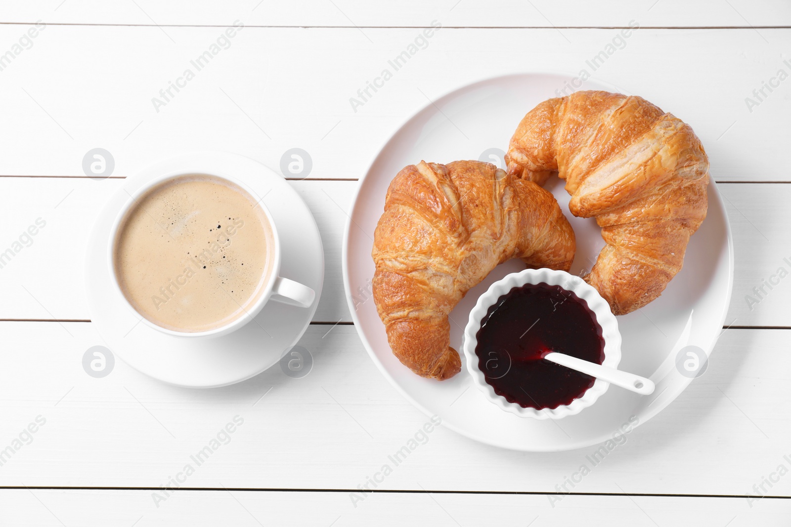 Photo of Fresh croissants, jam and coffee on white wooden table, flat lay. Tasty breakfast