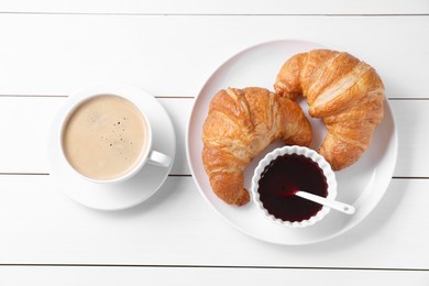 Photo of Fresh croissants, jam and coffee on white wooden table, flat lay. Tasty breakfast