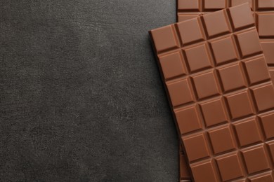 Delicious milk chocolate bars on black table, flat lay. Space for text