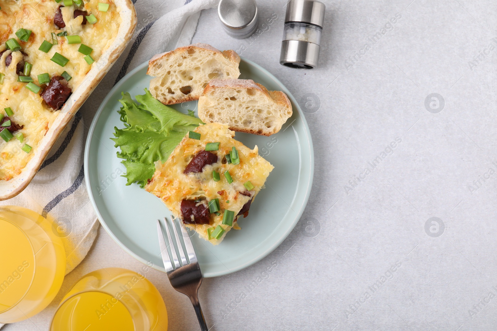 Photo of Tasty sausage casserole served on light grey table, flat lay. Space for text