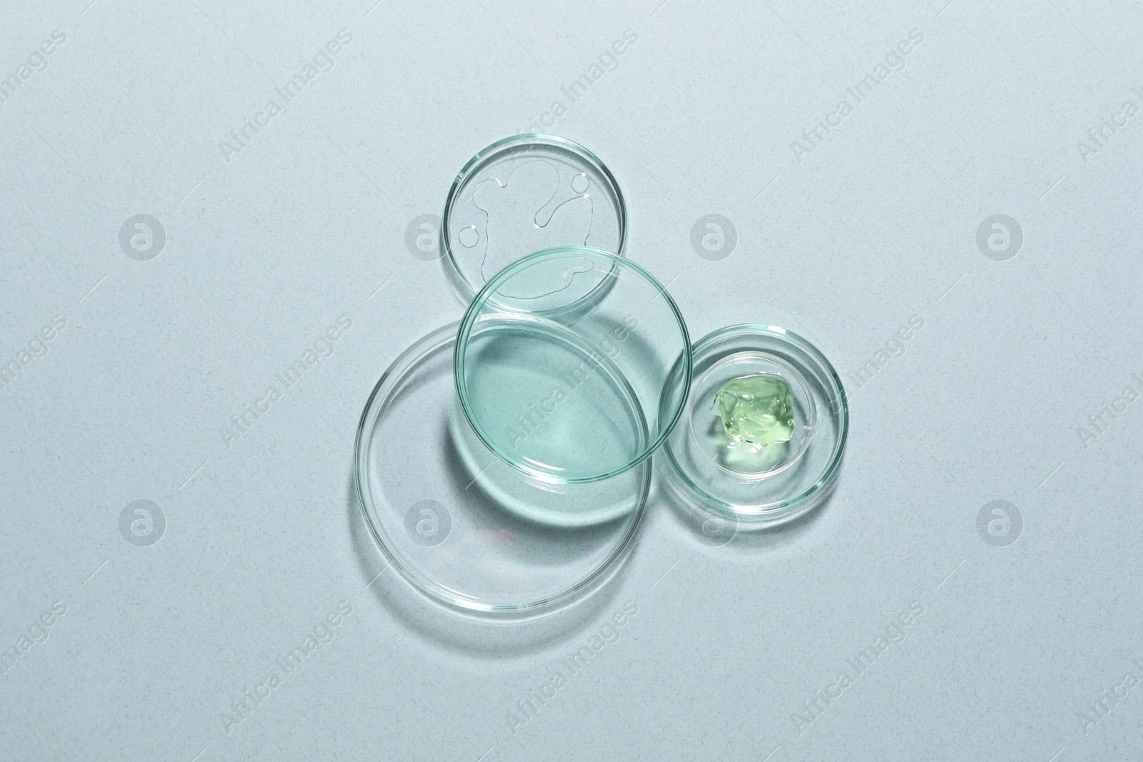 Photo of Organic cosmetic product and laboratory glassware on light background, flat lay