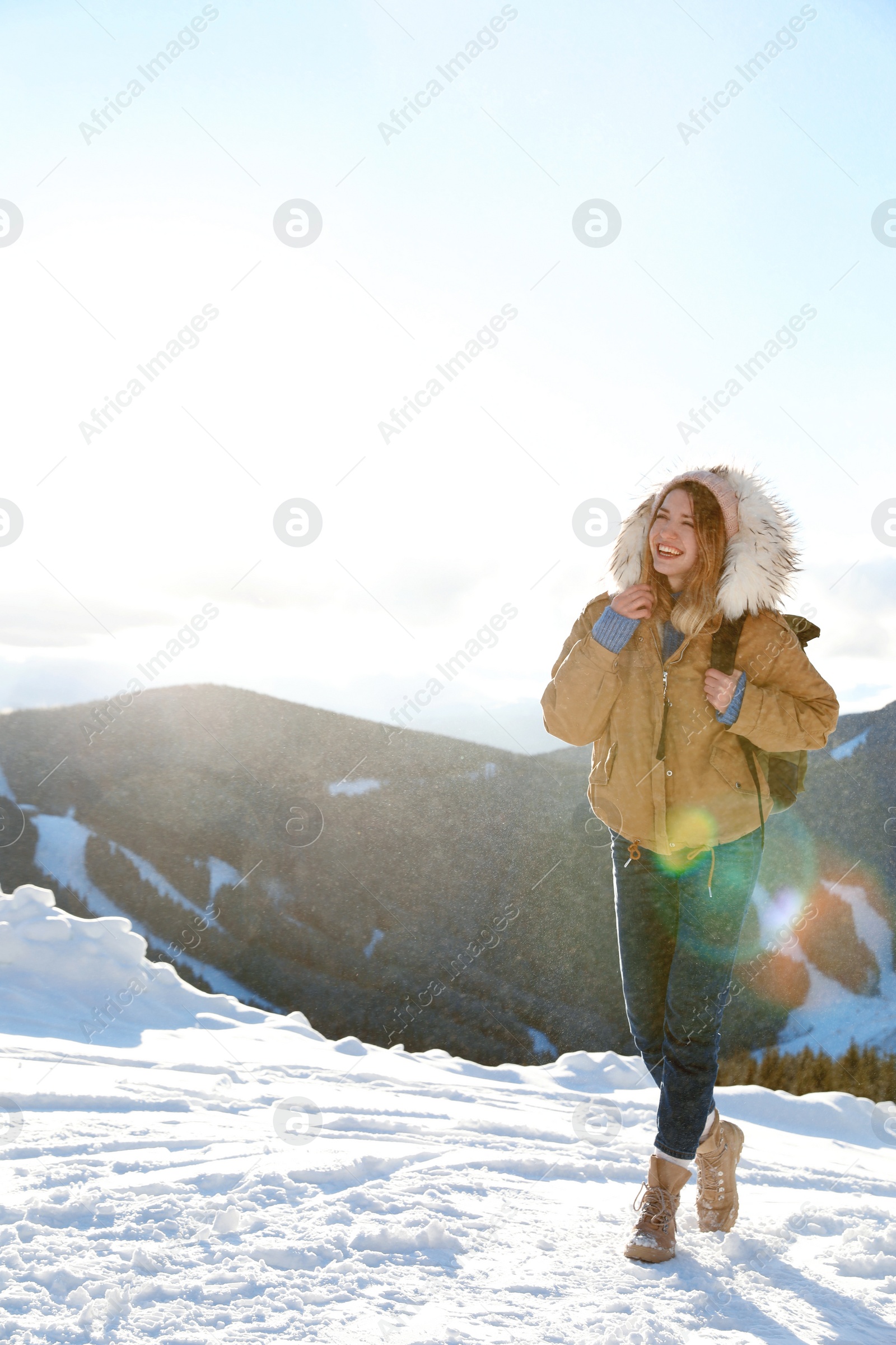 Photo of Happy young woman with backpack spending winter vacation in mountains. Space for text