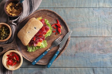Photo of Delicious sandwich with bresaola, lettuce and cheese served on light blue wooden table, flat lay. Space for text