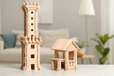 Photo of Wooden tower and house on light grey table indoors. Children's toys