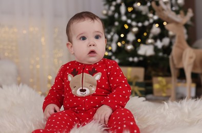 Photo of Baby in bright Christmas pajamas on floor at home