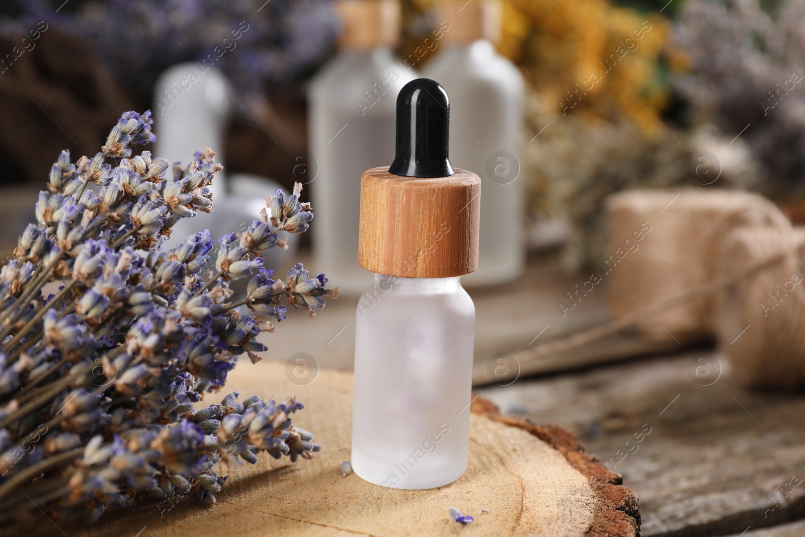 Photo of Bottle of essential oil and dry lavender flowers on wooden table, closeup. Medicinal herbs