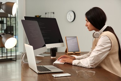 Photo of Programmer with headphones working at desk in office