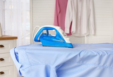 Photo of Clean shirt and iron on board indoors