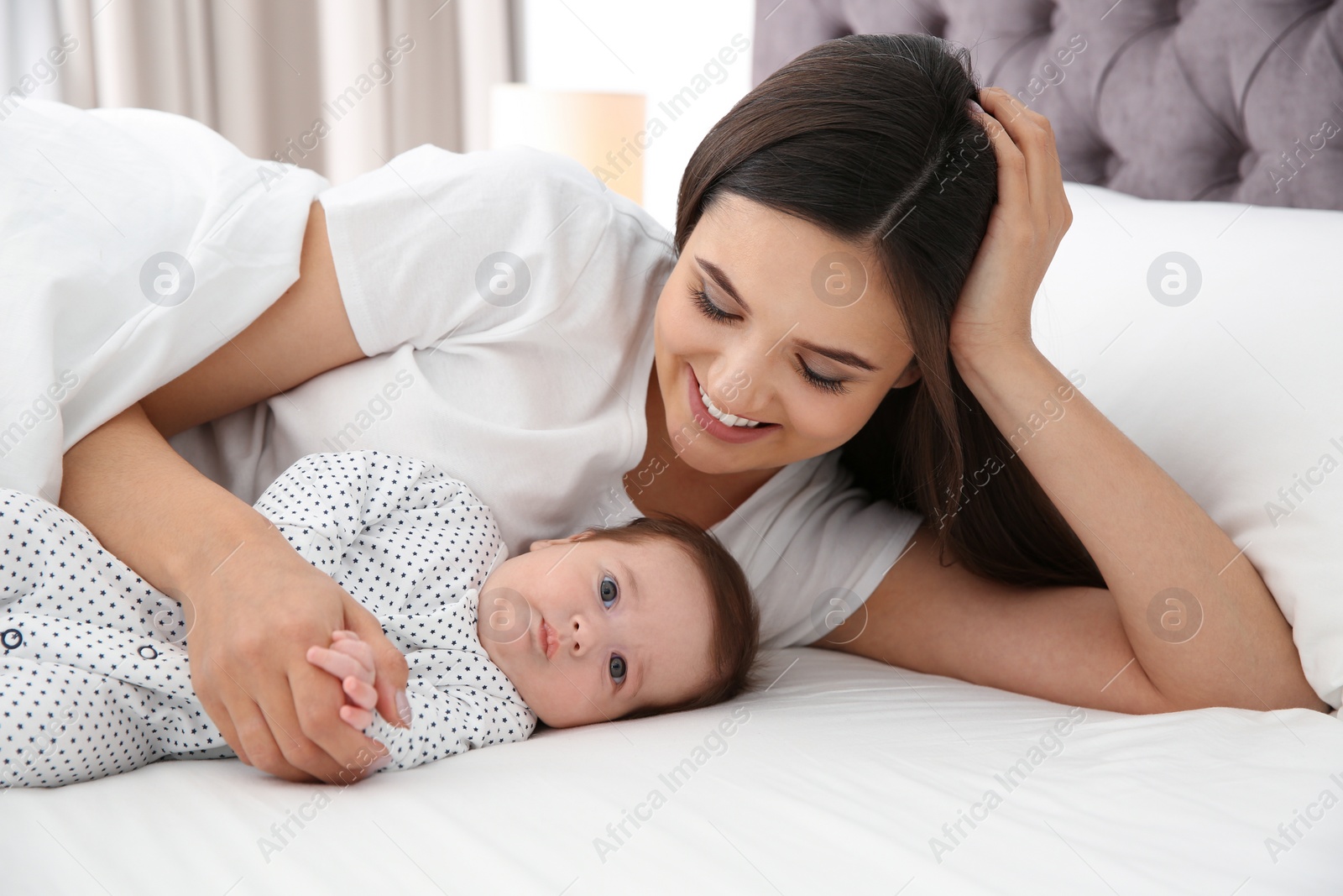 Photo of Happy woman with her cute baby on bed