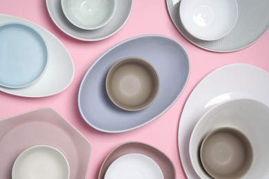 Photo of Different plates and bowls on pink background, flat lay