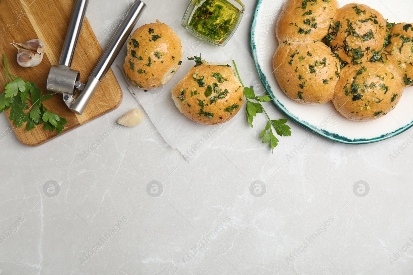 Photo of Traditional Ukrainian bread (Pampushky) with garlic on light grey marble table, flat lay. Space for text