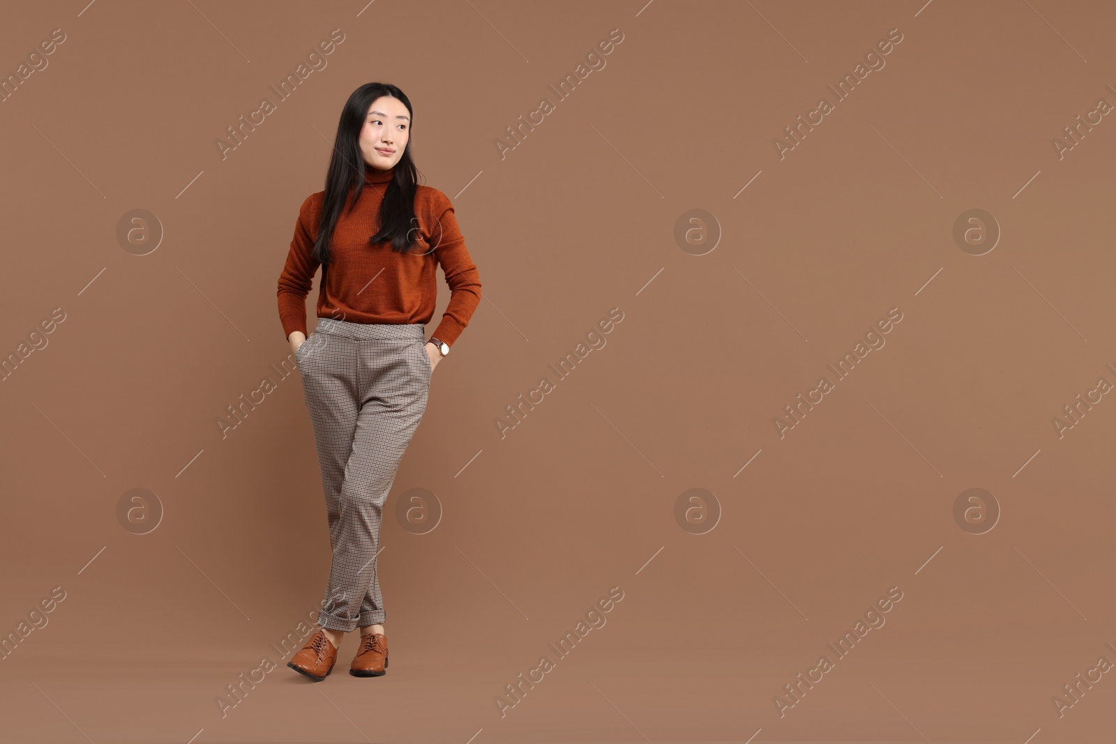 Photo of Full length portrait of beautiful woman on brown background. Space for text