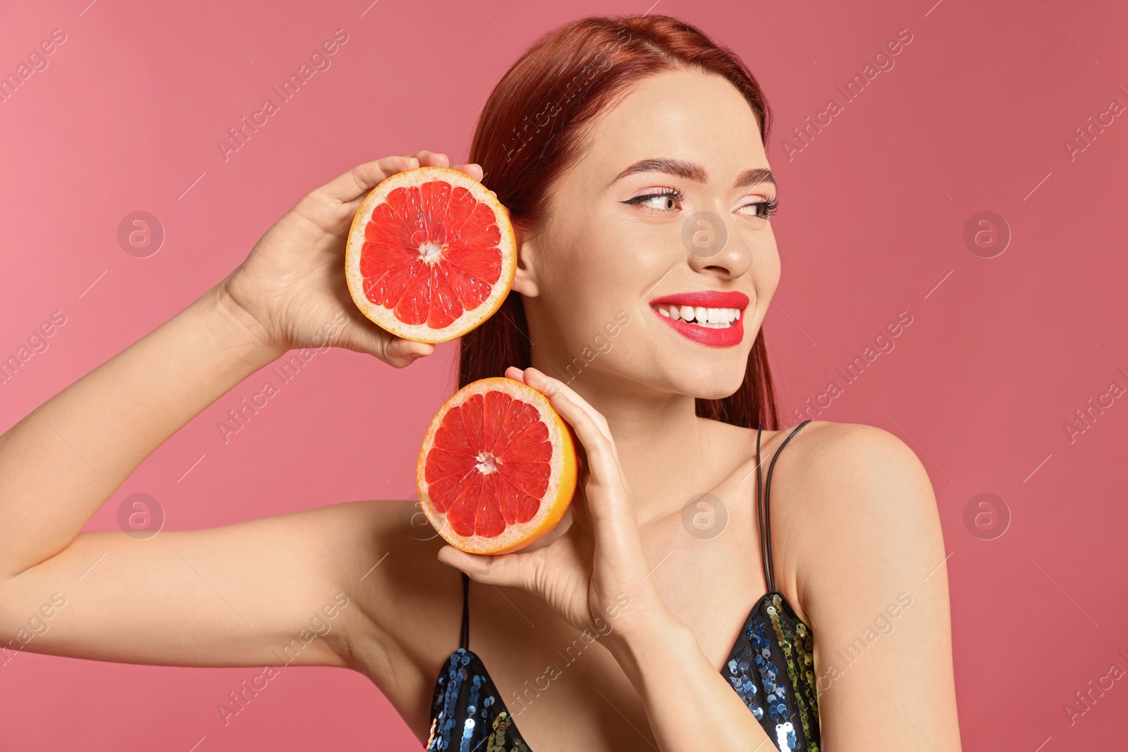 Photo of Happy woman with red dyed hair and grapefruits on pink background