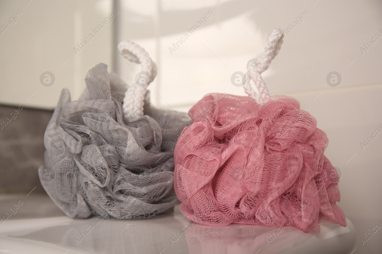 Photo of Colorful shower puffs on sink in bathroom, closeup