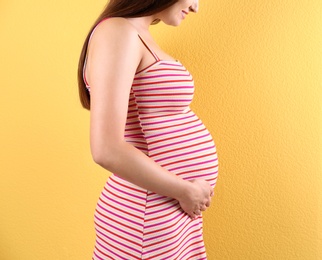 Photo of Young beautiful pregnant woman against color background, closeup