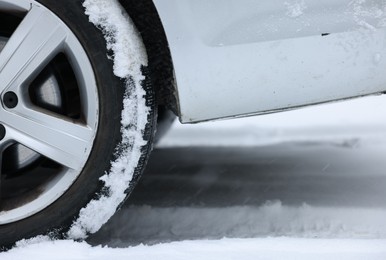Car with winter tires on snowy road, closeup