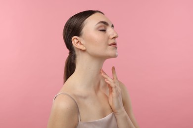 Beautiful woman touching her neck on pink background