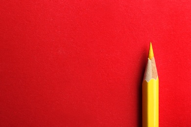 Photo of Yellow pencil on red background. Space for text