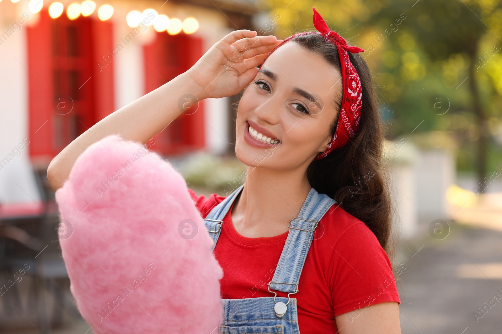 Photo of Stylish young woman with cotton candy outdoors