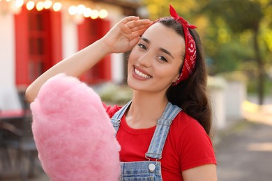 Stylish young woman with cotton candy outdoors