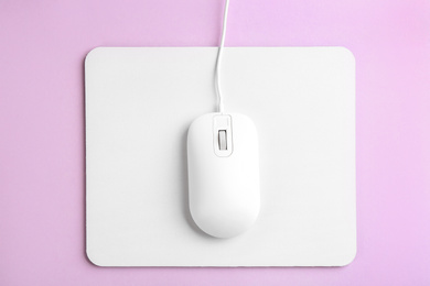Modern wired optical mouse and pad on lilac background, top view