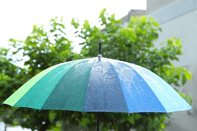 Photo of Open colorful umbrella outdoors on rainy day