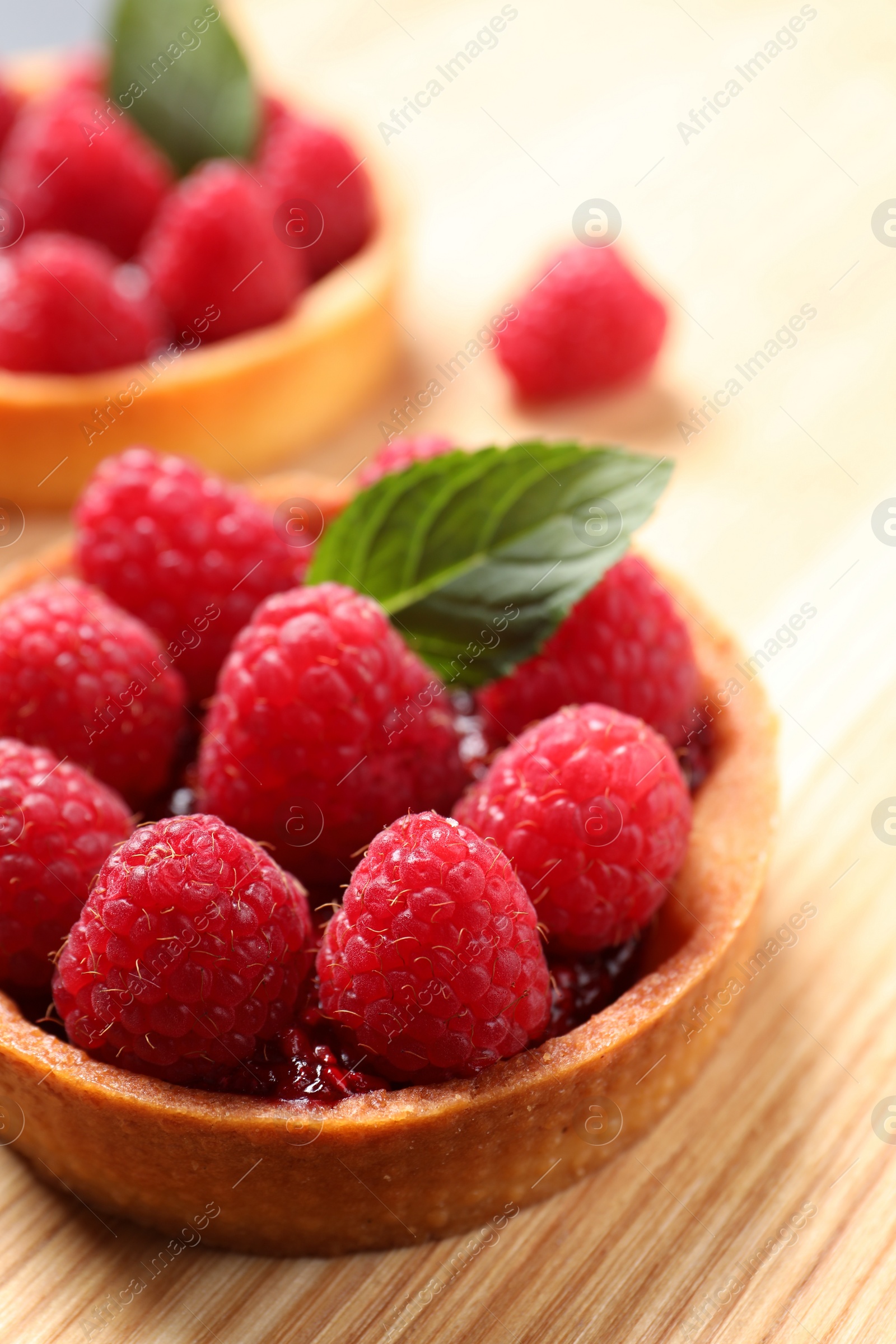 Photo of Tartlet with fresh raspberries on wooden table, closeup and space for text. Delicious dessert