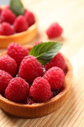 Photo of Tartlet with fresh raspberries on wooden table, closeup and space for text. Delicious dessert