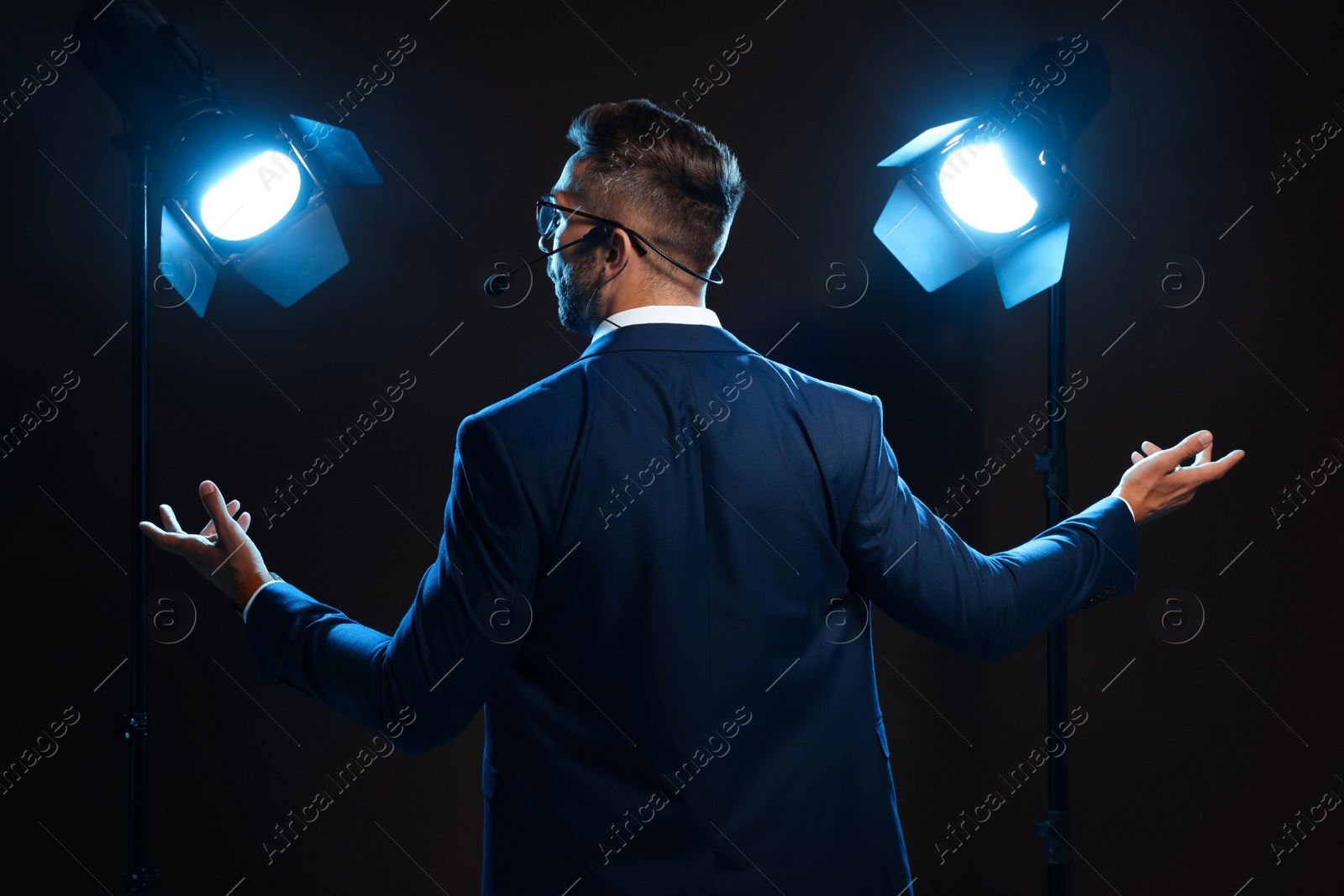 Photo of Motivational speaker with headset performing on stage, back view